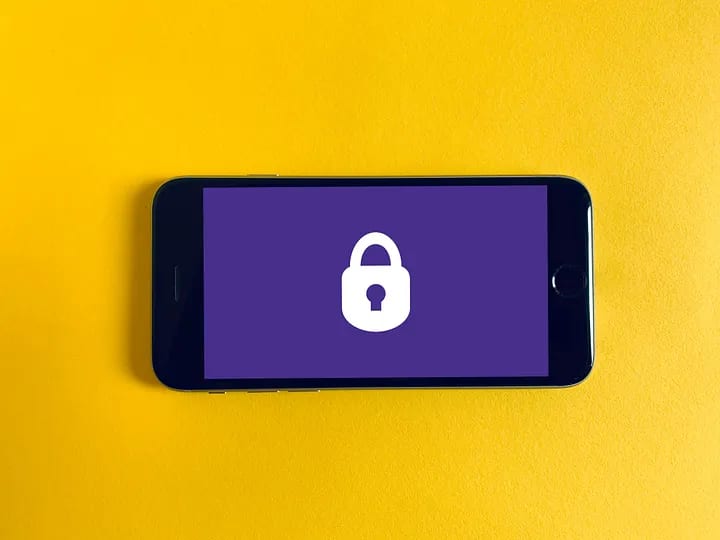A smartphone displaying a locked padlock icon on a purple screen, set against a vibrant yellow background.